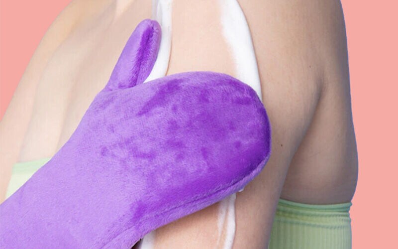 Selbstbräuner wird mit einem Handschuh aufgetragen
